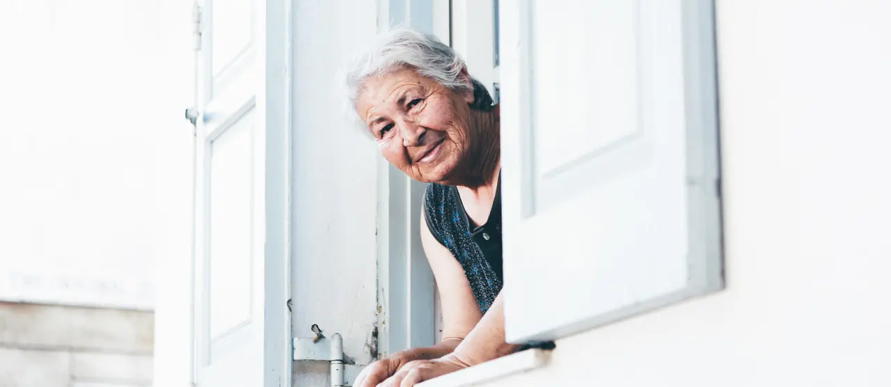 idős nő néz ki az ablakon